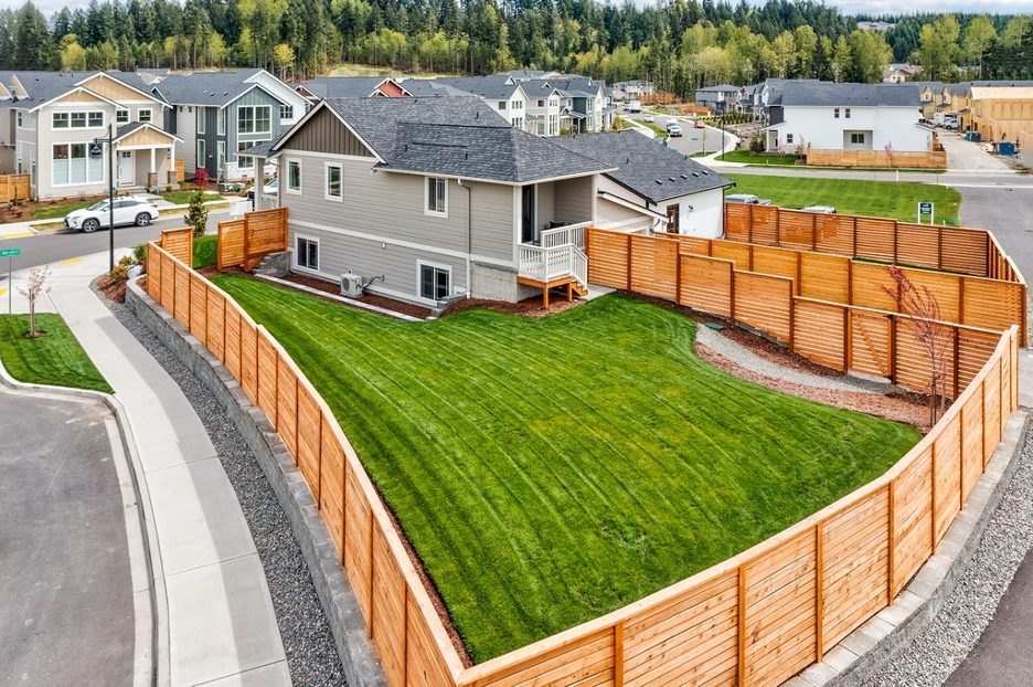 Exterior view of a cost-efficient single-family home at Eagle Ridge in Tehaleh, demonstrating sloped-lot grading to reduce construction costs, courtesy of ImageArts Productions and NHTI.